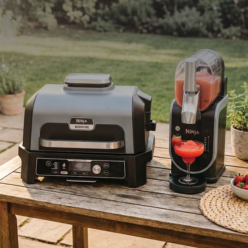 Ninja Woodfire grill and SLUSHi machine on an outdoor table, mid-demo